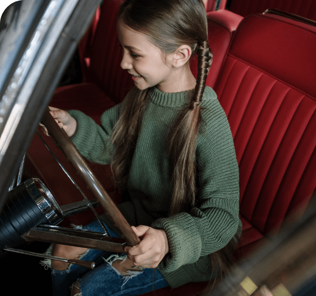 Mädchen auf einem roten Fahrersitz im restaurierten Fahrzeug